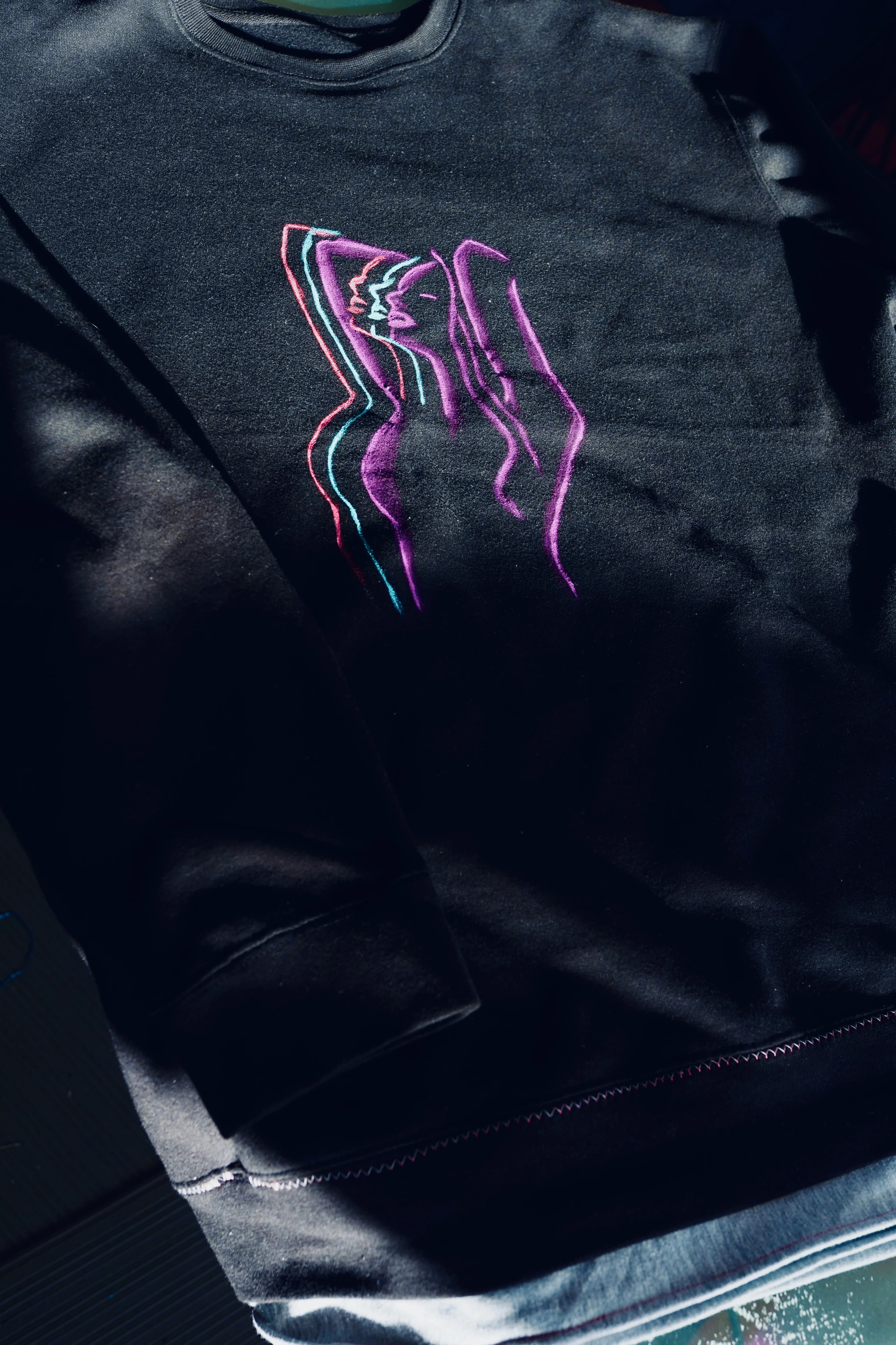 Black crewneck sweatshirt with minimalist embroidered neon linear kissing figures